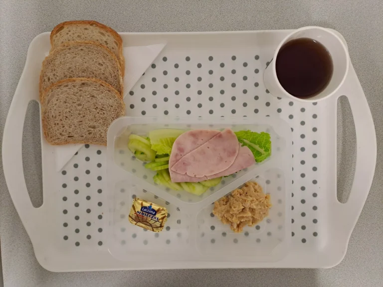 Śniadanie, dieta podstawowa: herbata czarna b/c -250ml, chleb graham-70g (sezam, gluten), chleb pszenny- 30g (gluten), margaryna 60 % tł. 10 g, smalczyk z fasoli 50 g, szynka z indyka 40 g (soja), sałata rzymska 20g, ogórek świeży 80g